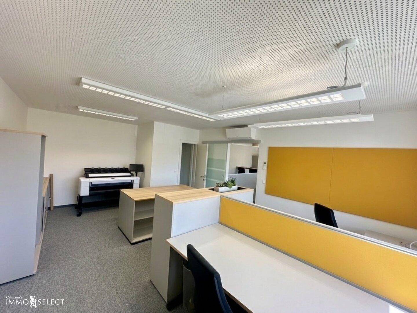 Helles Büro mit modernen Arbeitsplätzen, gelben Akzenten und Druckerstation.