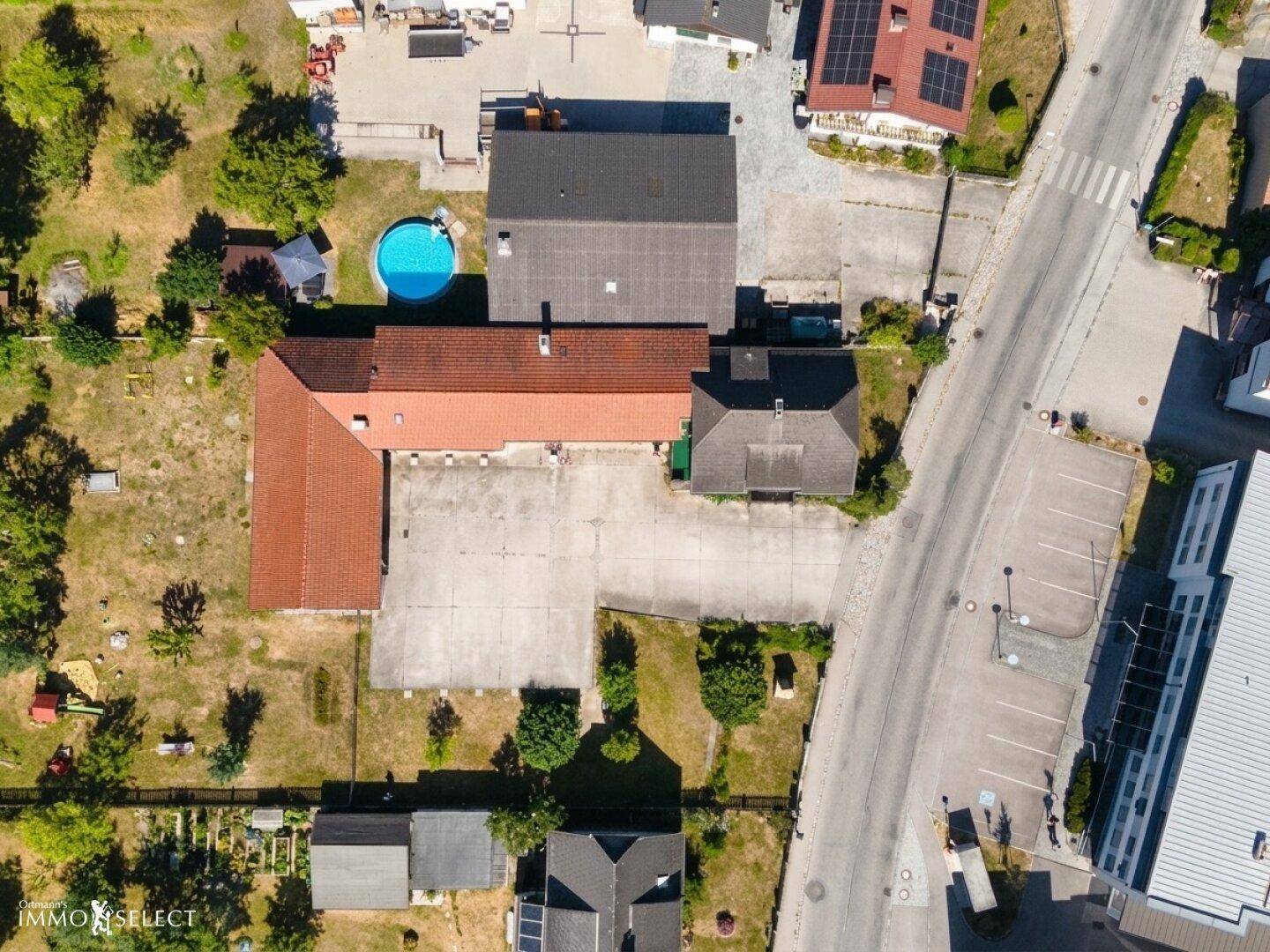 Luftaufnahme eines Anwesens mit mehreren Gebäuden, einem Pool und großzügigen Freiflächen.