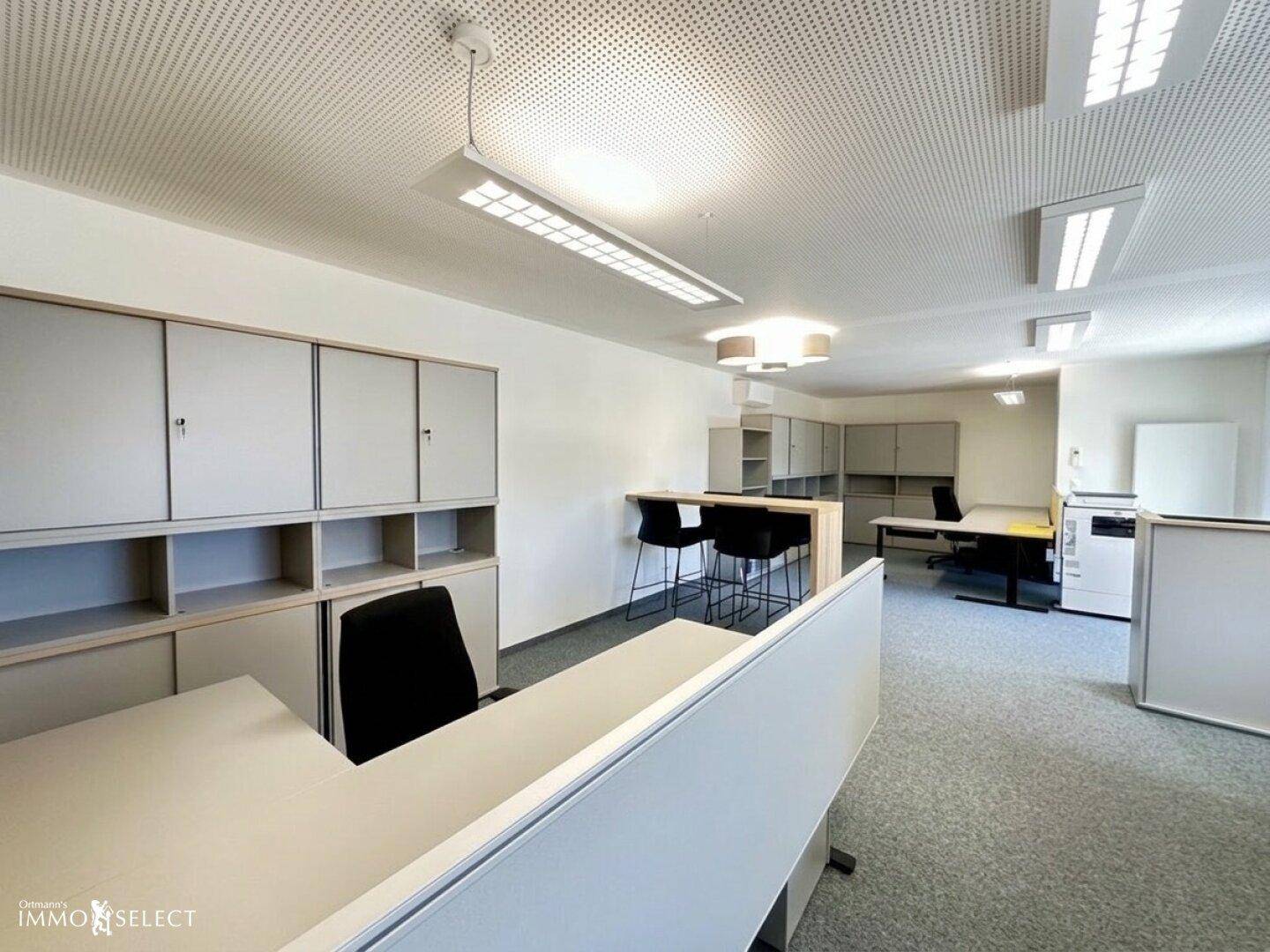 Helles Büro mit zahlreichen Schränken, modernen Arbeitsplätzen und Teppichboden.