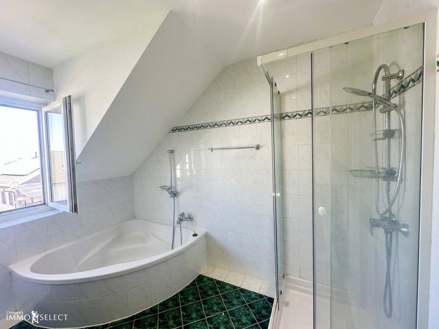 Badezimmer im Dachgeschoss mit Eckbadewanne, Duschkabine und Fenster.