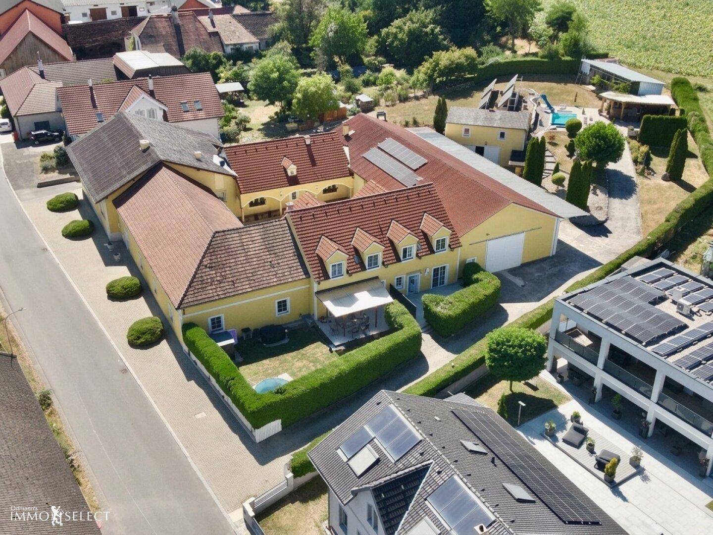Luftaufnahme des großen Anwesens mit mehreren Gebäuden, Pool und Photovoltaikanlagen.