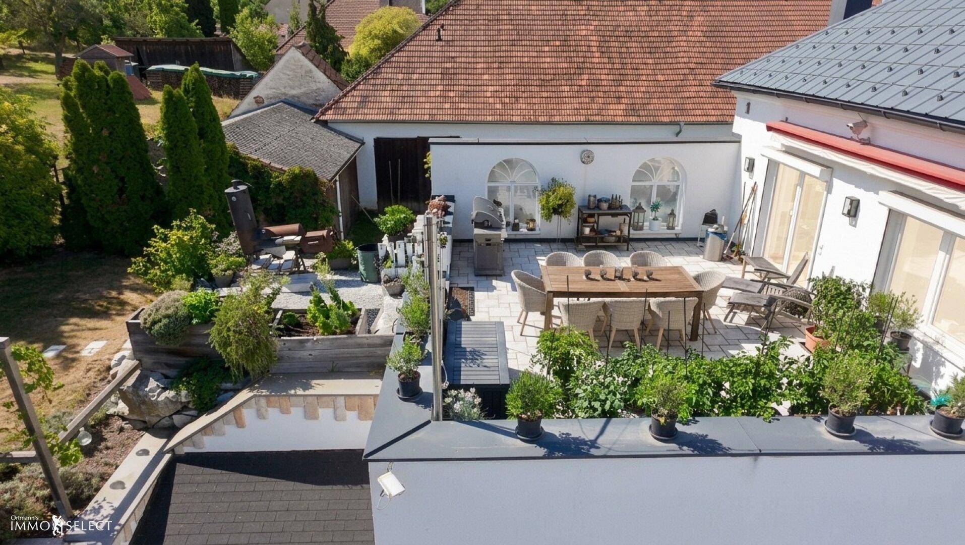 Luftaufnahme des Anwesens mit großer Terrasse, Garten und umliegender Bebauung.