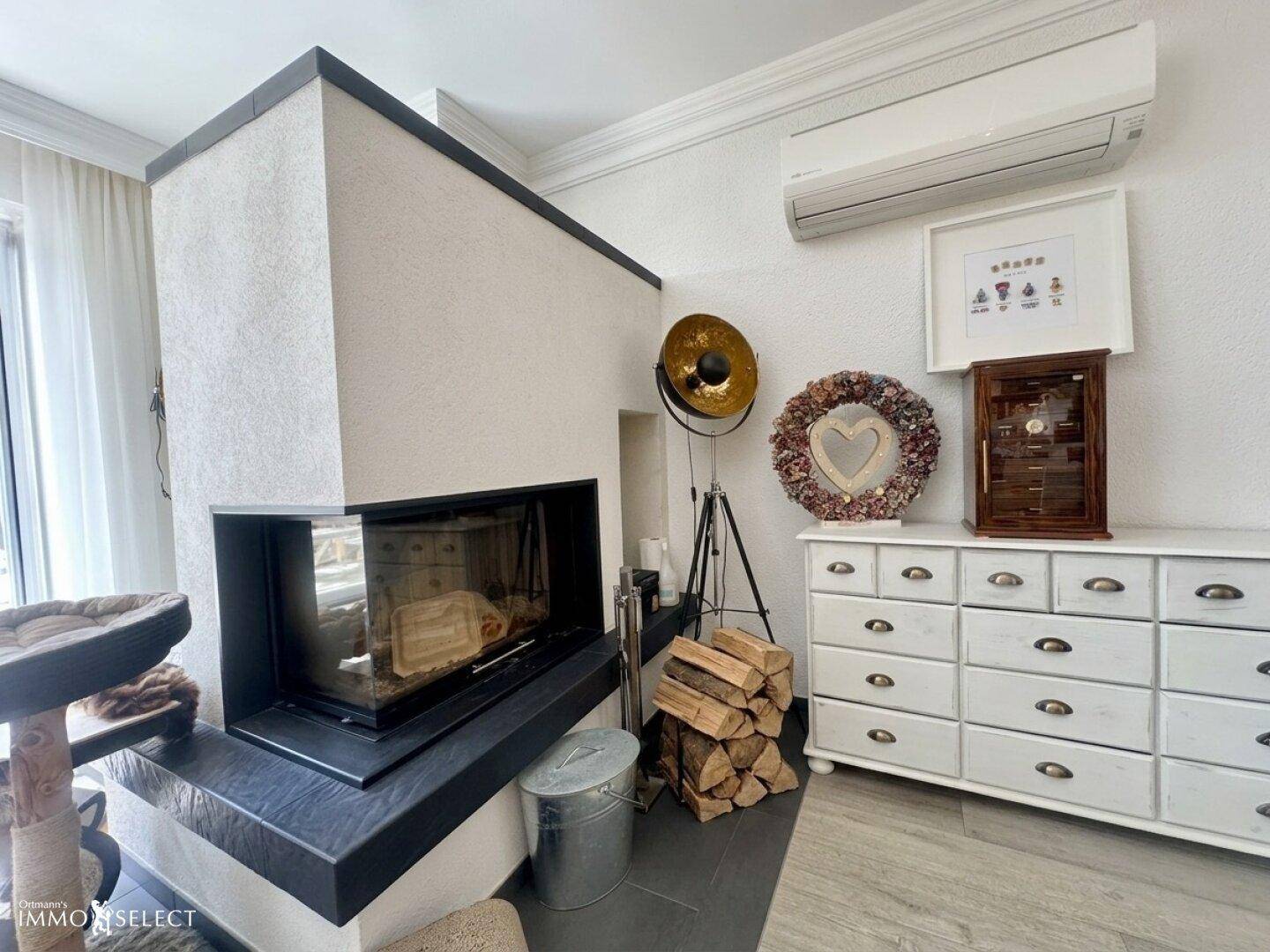 Gemütliches Wohnzimmer mit modernem Kamin, Klimaanlage und stilvoller Dekoration.