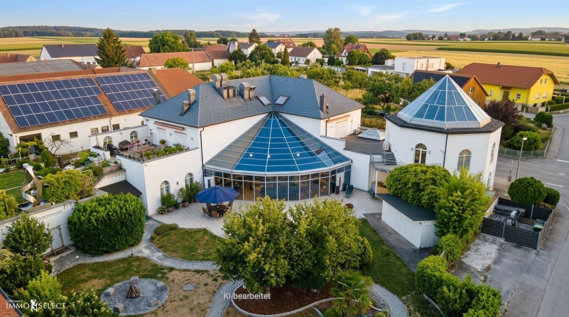 Luftaufnahme des Anwesens mit weitläufigem Garten, Wintergarten und umliegender ländlicher Bebauung.