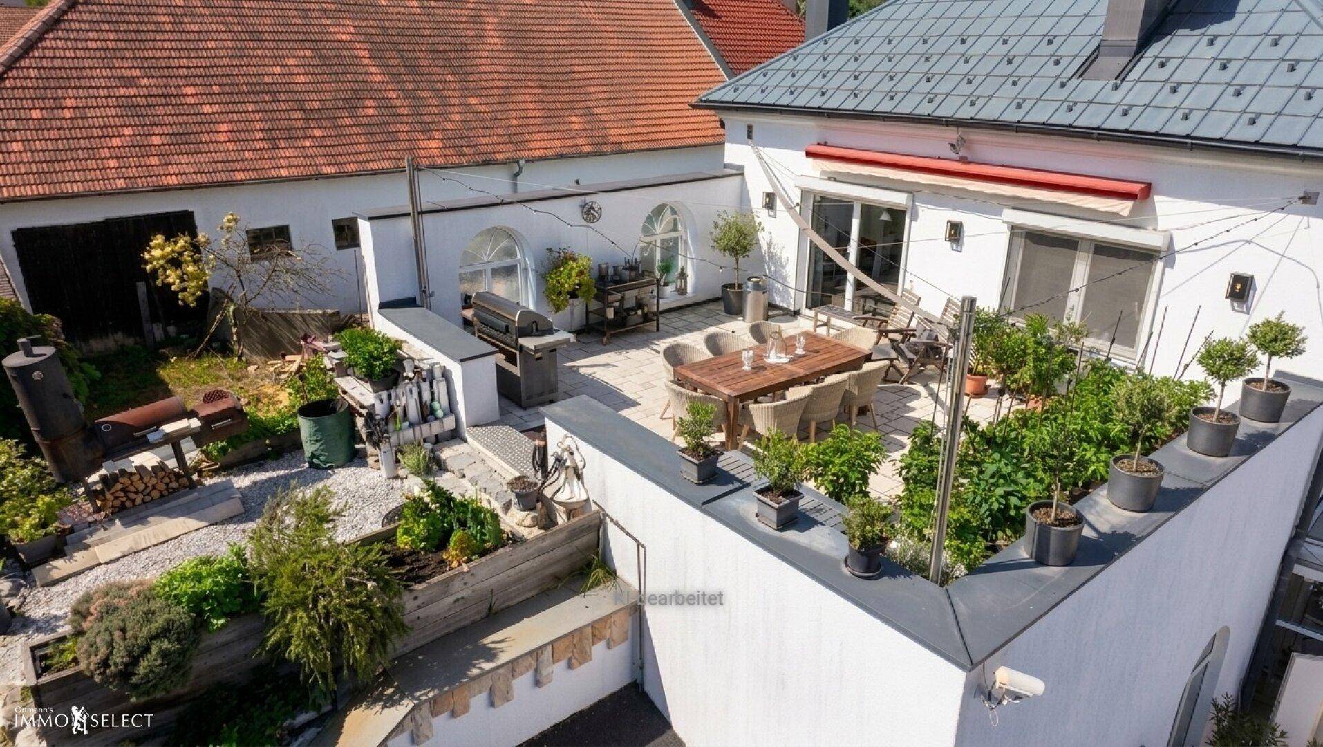 Große Dachterrasse mit Essbereich, Grill und bepflanzten Töpfen, angrenzend an den Garten.