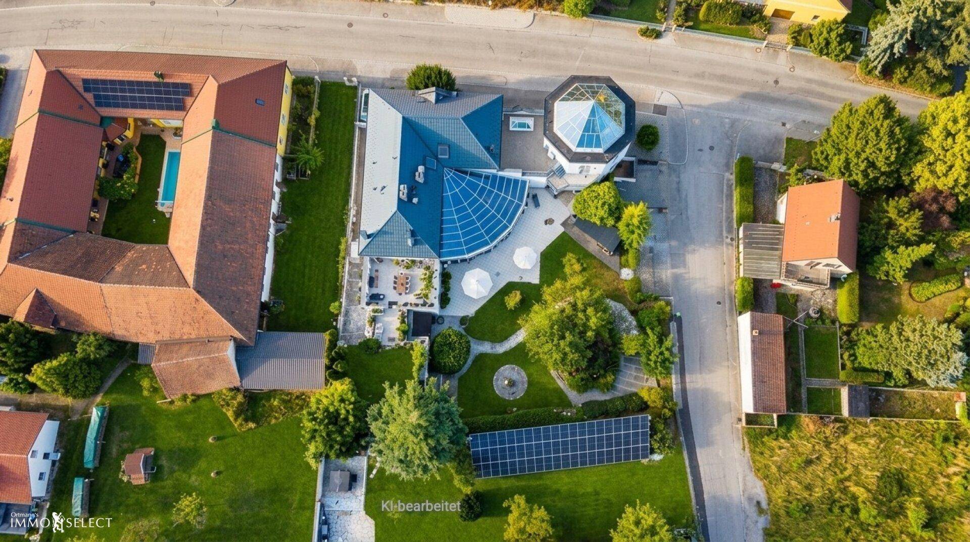 Vogelperspektive des Anwesens mit Hauptgebäude, Solaranlage und gepflegten Gartenbereichen.