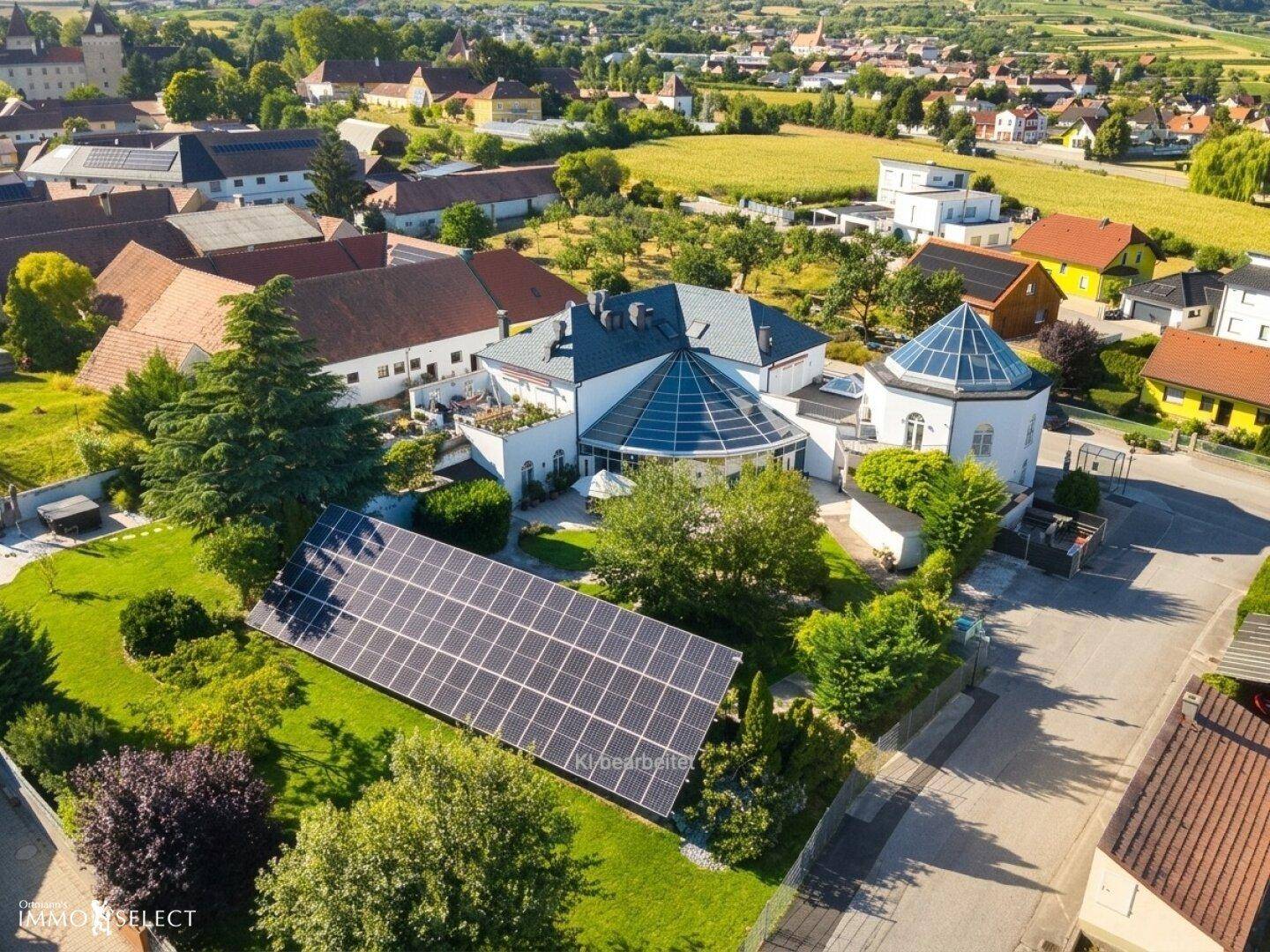Luftaufnahme des Anwesens mit Solaranlage im Garten und Blick auf das umliegende Dorf.