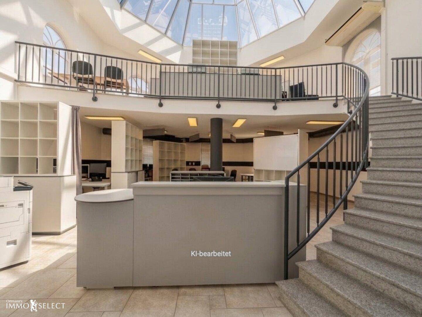 Empfangsbereich mit geschwungener Treppe zur Galerie und viel Tageslicht durch die Glasdecke.