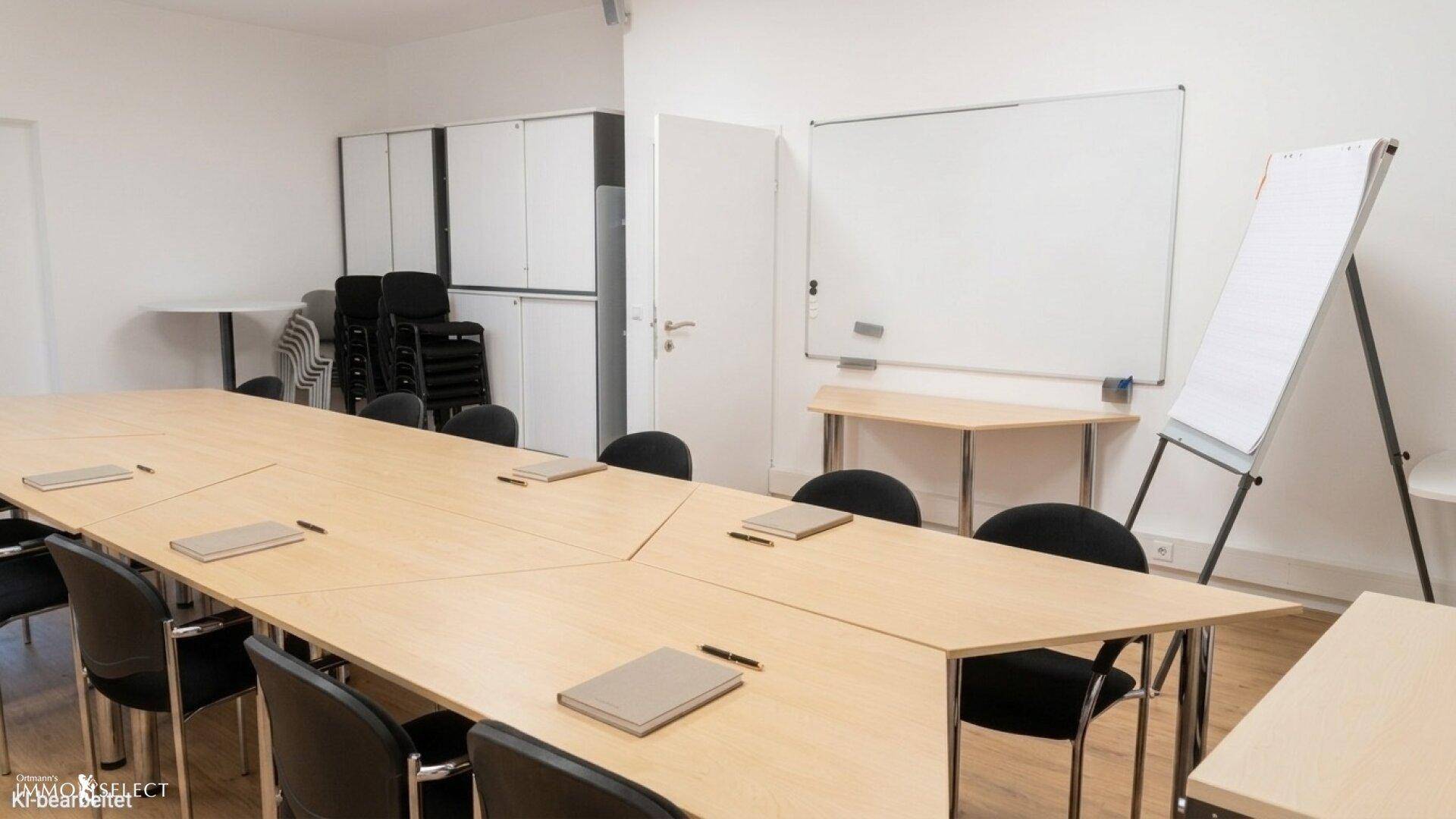 Heller Konferenzraum mit großem Tisch, Whiteboard und Stauraum für Büromaterialien.