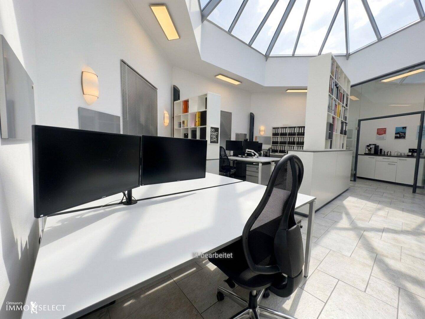 Offener Bürobereich mit mehreren Arbeitsplätzen, Glasdach und moderner Einrichtung.
