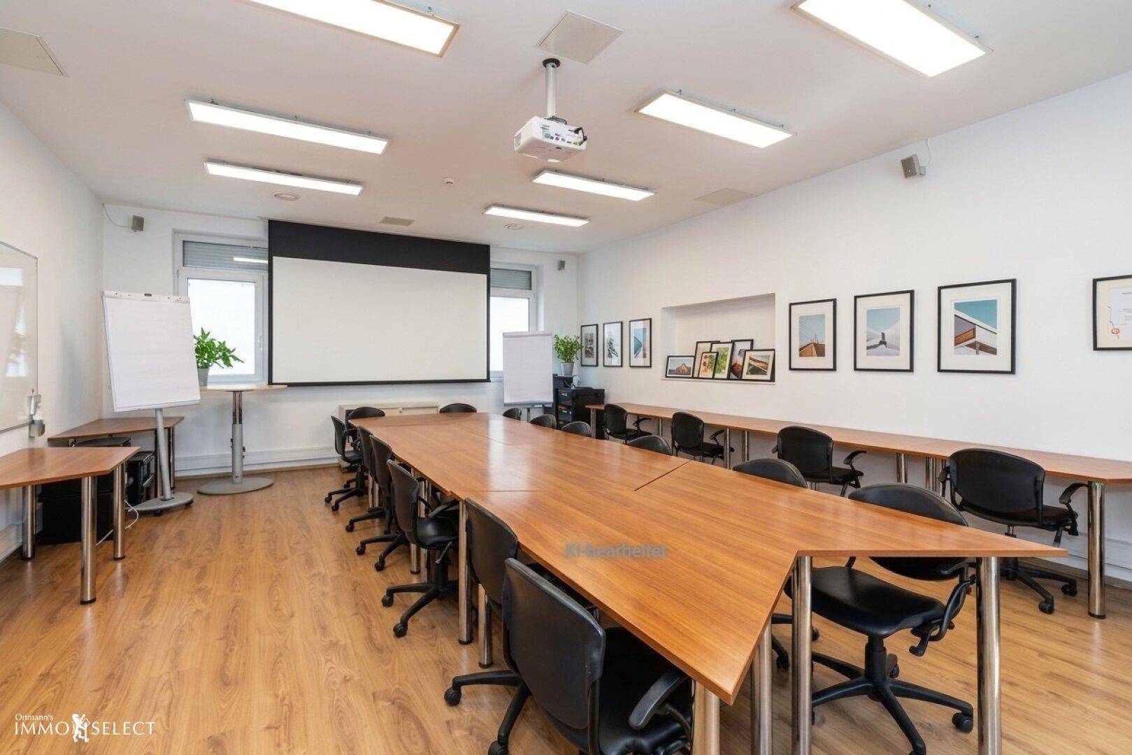 Geräumiger Konferenzraum mit großem Holztisch, Projektor und Leinwand für Präsentationen.