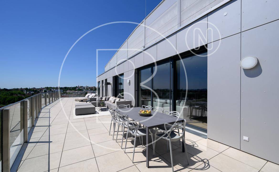 Weitläufige Dachterrasse mit Essbereich und Lounge-Möbeln, angrenzend an eine moderne Fassade.