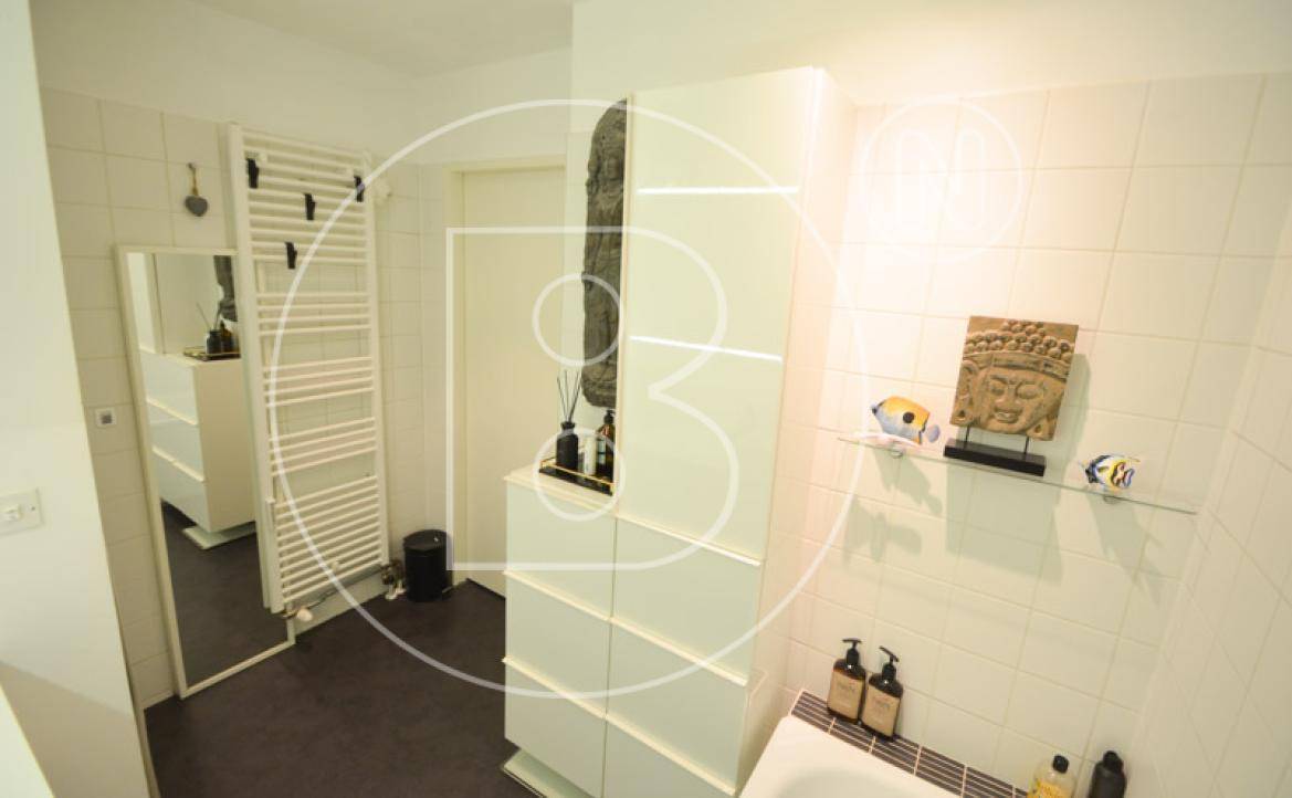 Helles Badezimmer mit Badewanne, beheiztem Handtuchhalter und praktischem Stauraum.
