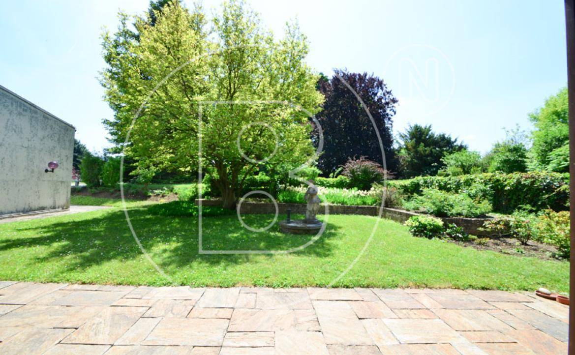 Große gepflasterte Terrasse mit Blick auf den weitläufigen, grünen Gartenbereich.