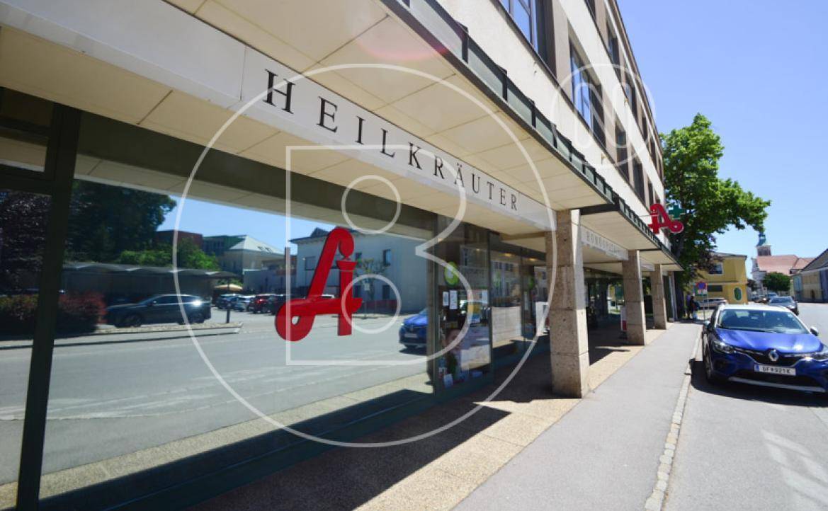 Schaufenster des Erdgeschosses mit Reflexionen der Straße und vorbeifahrenden Autos.