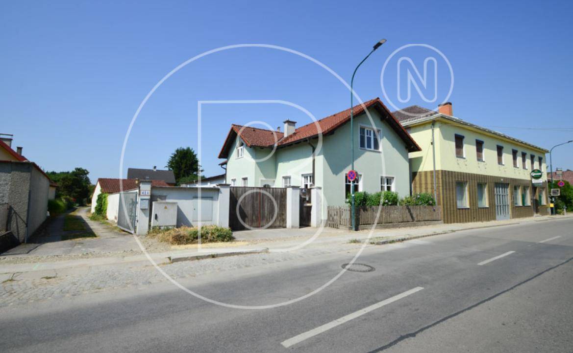 Ansicht des Hauses von der Straße mit angrenzendem Gebäude und Zufahrt.