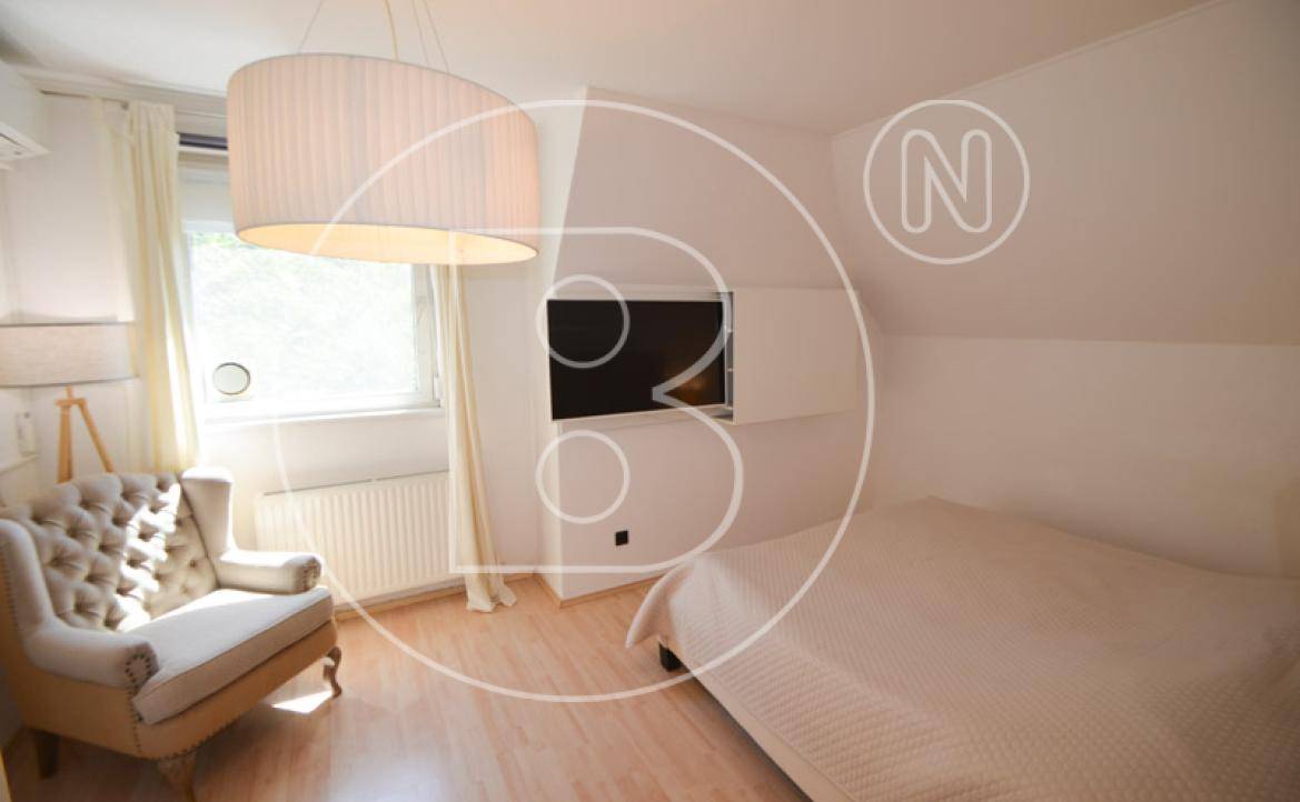 Helles Schlafzimmer mit Holzboden, großem Fenster und einem bequemen Sessel.