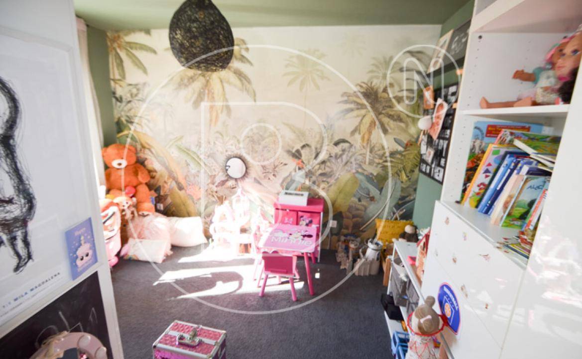 Kinderzimmer mit Dschungel-Tapete, Spielzeug und einem kleinen Schreibtisch.