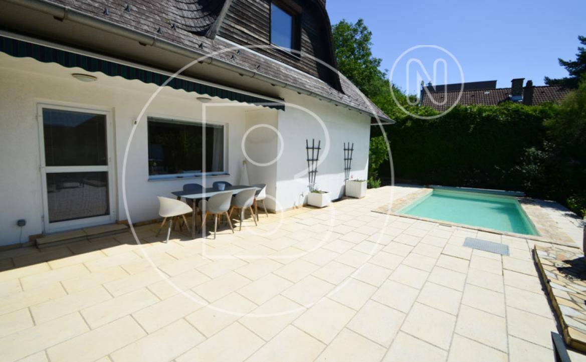 Weitläufige, gepflasterte Terrasse am Haus mit Essbereich und direktem Zugang zum Poolbereich.
