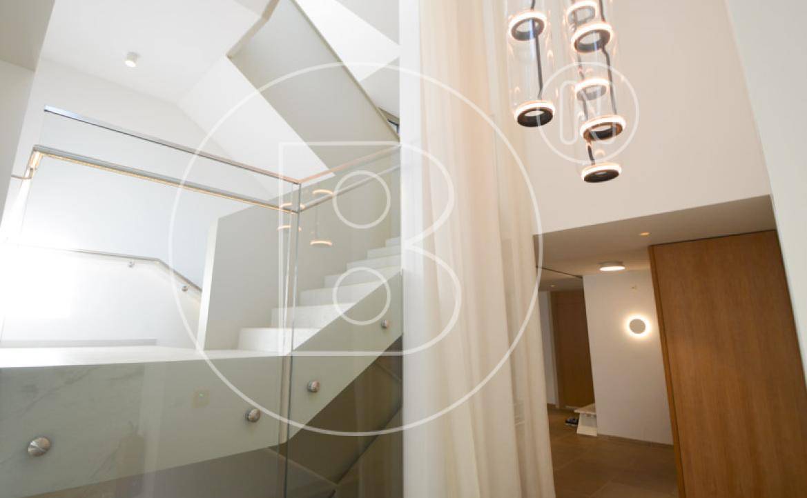 Elegante Treppe mit Glasgeländer und stilvoller Beleuchtung, die den modernen Charakter unterstreicht.