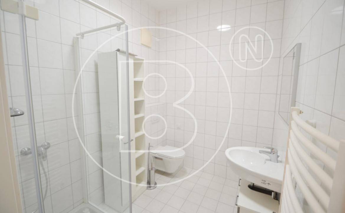 Modernes Badezimmer mit weißen Fliesen, Duschkabine, WC und Waschbecken.