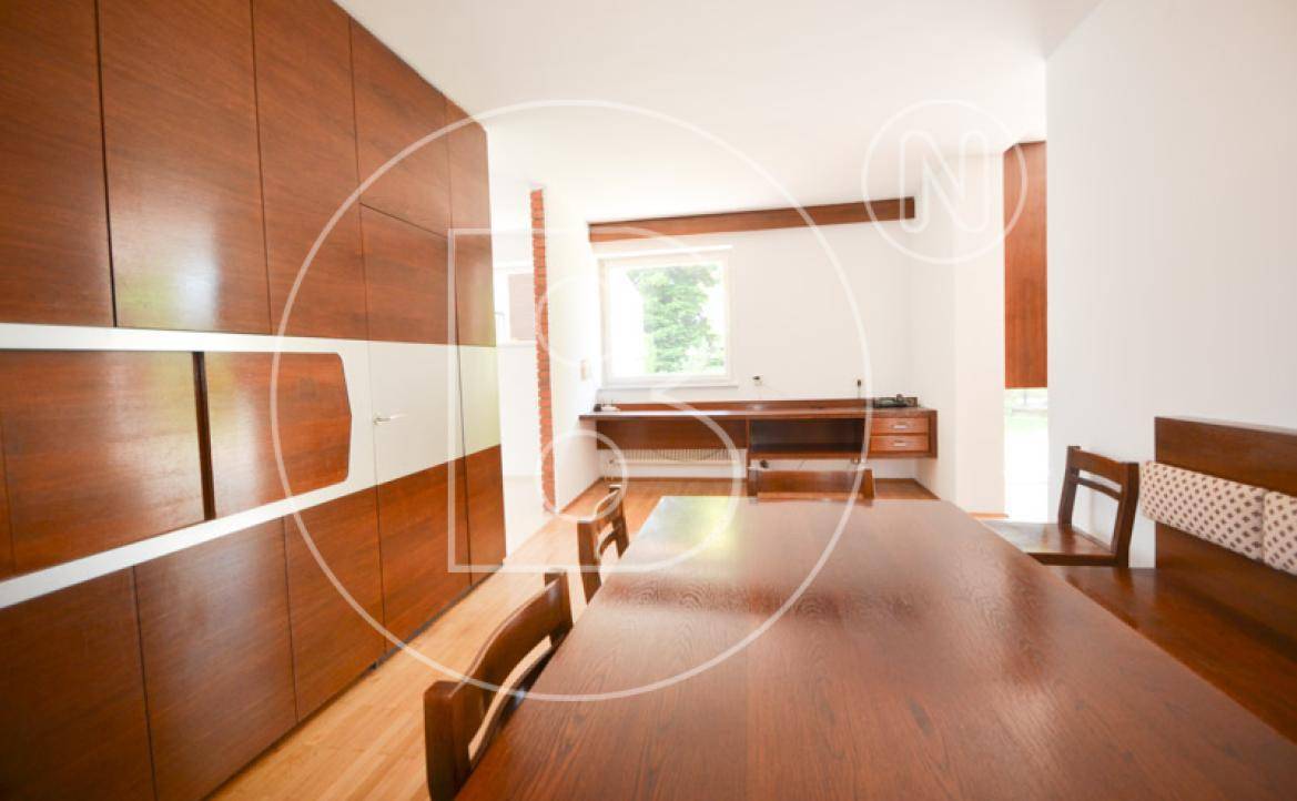 Esszimmer mit Holztisch und Stühlen, umgeben von eleganten Holzschränken und einem Fenster.