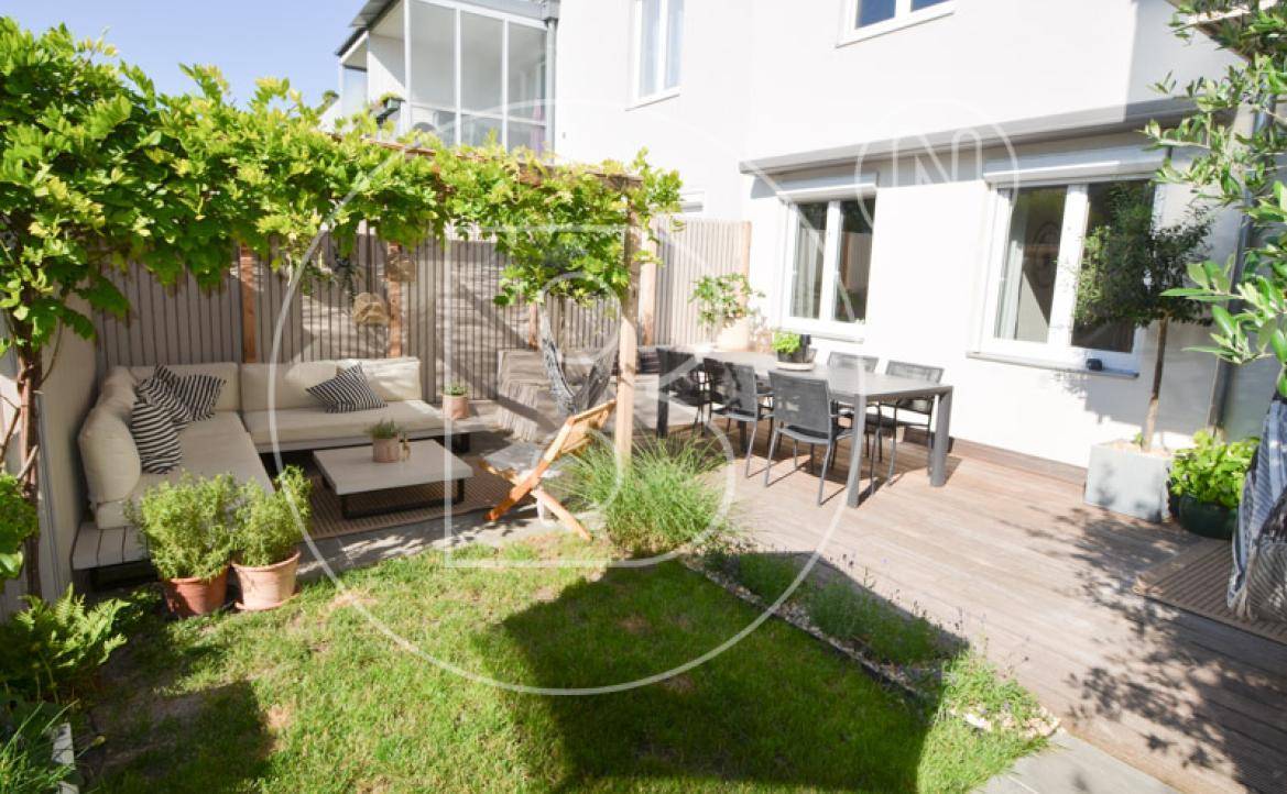 Gemütliche Holzterrasse mit Lounge-Bereich, Esstisch und begrüntem Pergola-Dach.