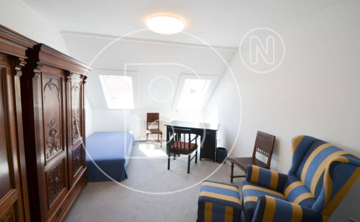 Schlafzimmer im Dachgeschoss mit Dachfenstern, Holzkleiderschrank und Sessel.