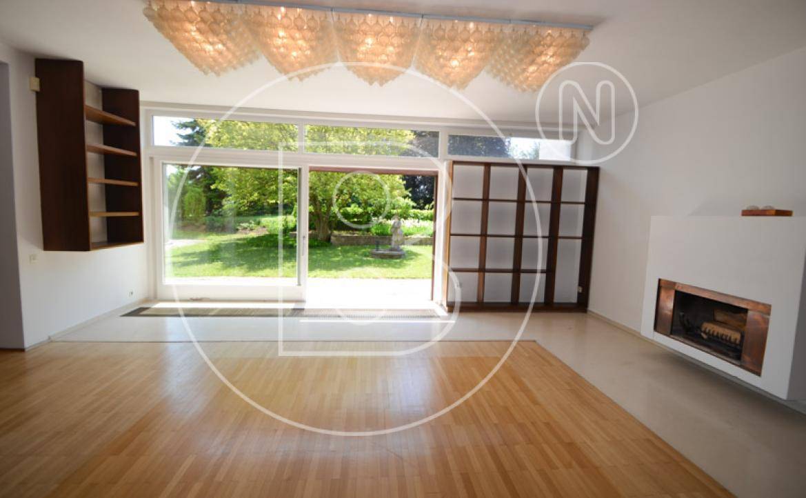 Wohnzimmer mit großen Schiebetüren, die direkten Zugang zum Garten und viel Tageslicht ermöglichen.
