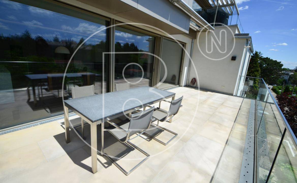 Moderne Terrasse mit Esstisch und Stühlen, umgeben von Glasgeländer und großen Schiebetüren.