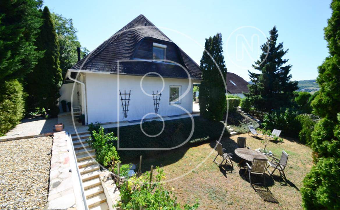 Gartenbereich des Hauses mit Mansarddach, Sitzgelegenheiten und altem Baumbestand.