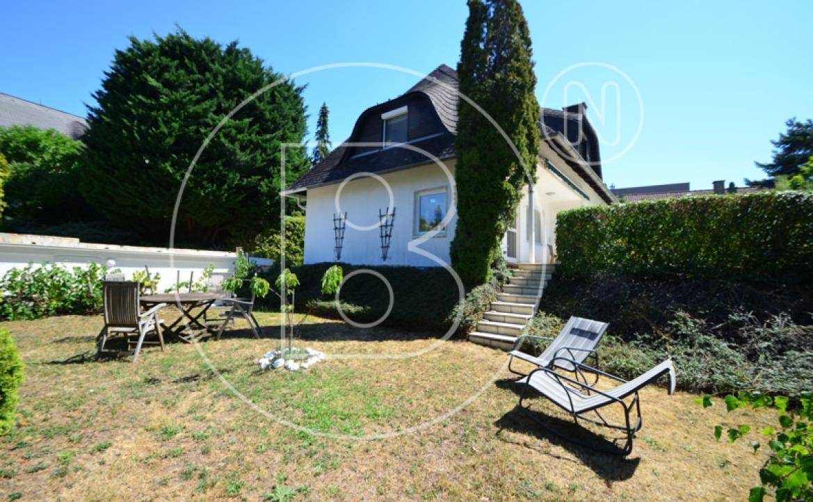 Blick vom Garten auf das charmante Haus mit Mansarddach und einer Außentreppe zur Terrasse.
