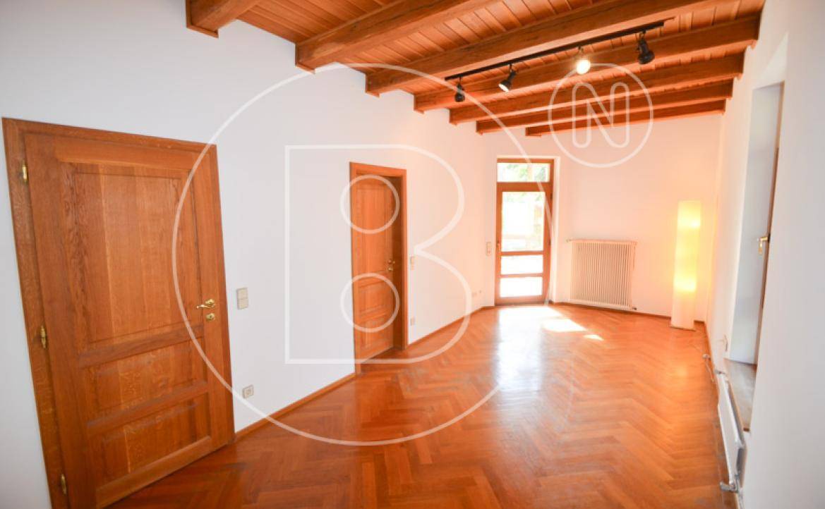 Geräumiges Zimmer mit Fischgrätparkett, Holztüren und sichtbaren Deckenbalken.
