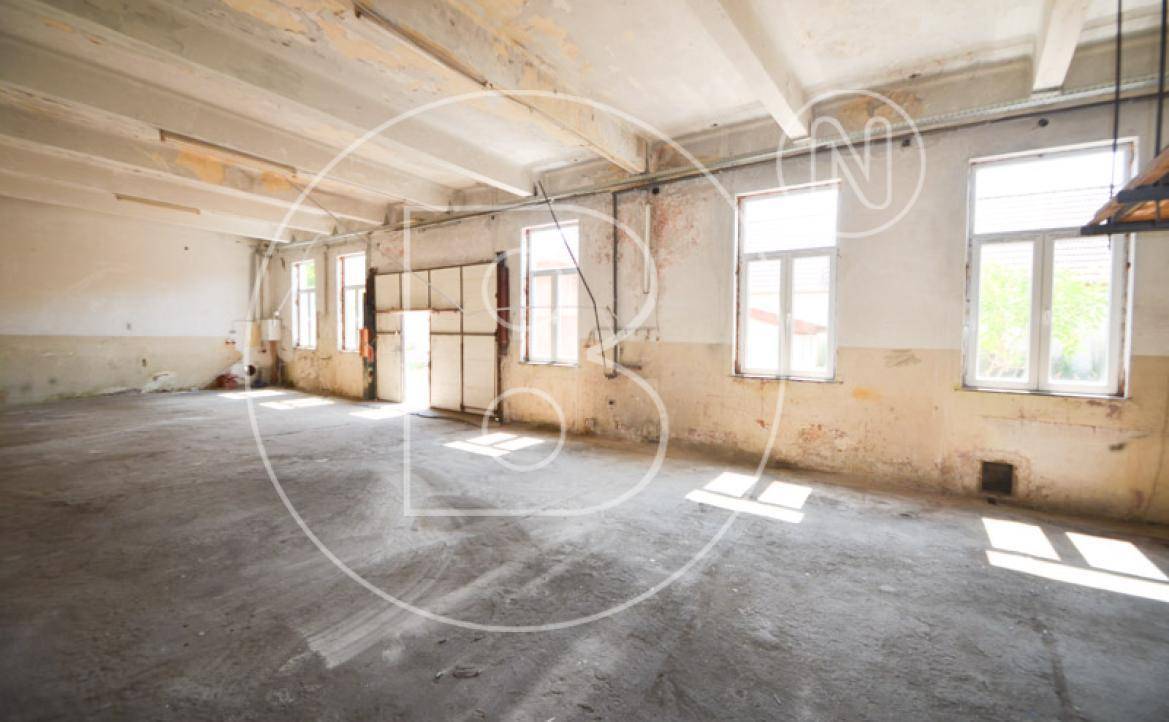 Große Lagerhalle oder Werkstatt mit Betonboden und hohen Decken, renovierungsbedürftig.
