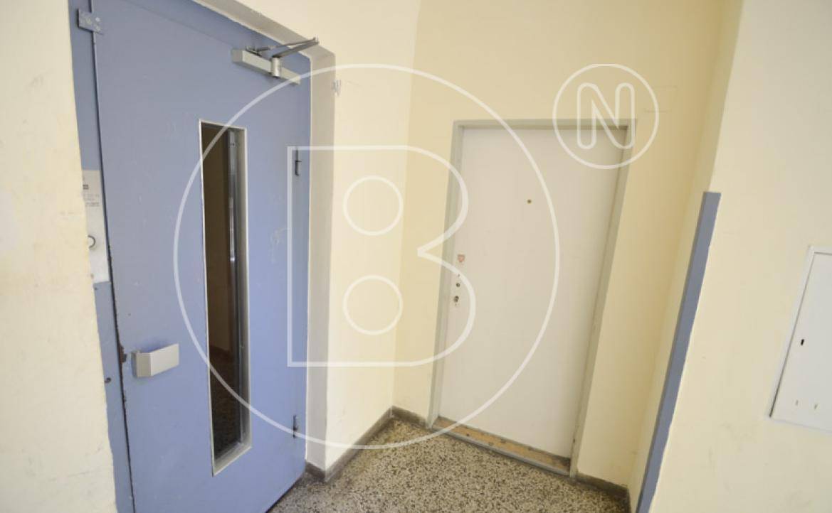 Flur im Treppenhaus mit zwei Türen und Terrazzoboden, bietet Zugang zu den Wohneinheiten.