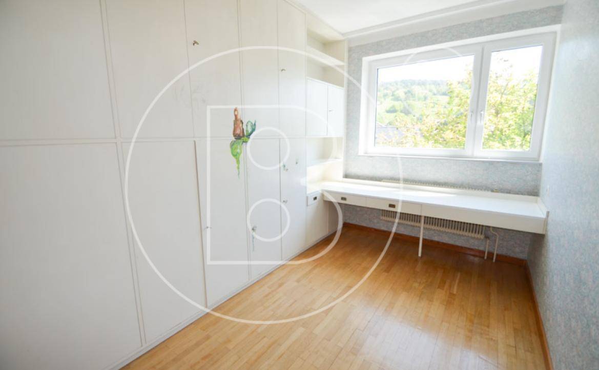Geräumiges Zimmer mit Holzboden, großen Einbauschränken und Fenster mit Blick ins Grüne.