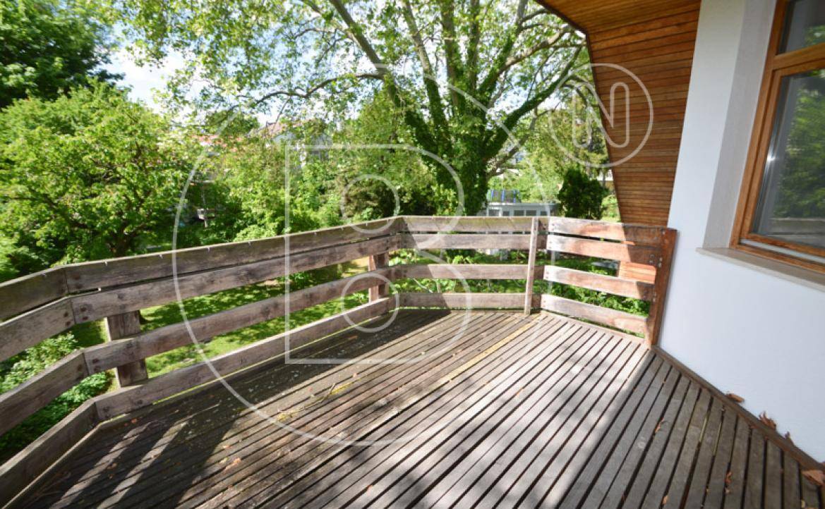 Geräumiger Holzbalkon mit Blick ins Grüne, ideal zum Entspannen im Freien.