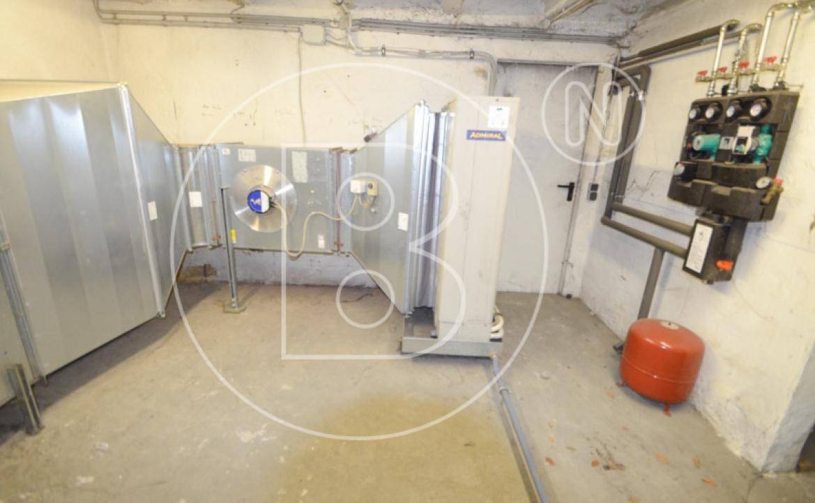 Technikraum im Keller mit Heizungsanlage, Lüftungskomponenten und einem roten Ausdehnungsgefäß.