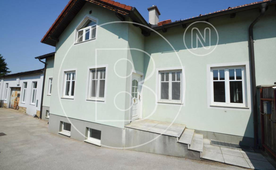 Eingangsbereich des Hauses mit Treppe, Rampe und hellgrüner Fassade.