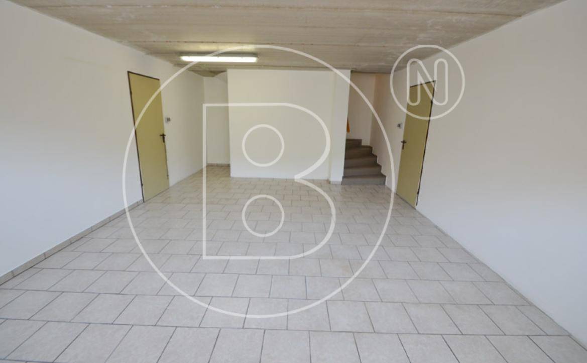 Großer Kellerraum mit Fliesenboden und Zugang zu weiteren Räumen und Treppen.