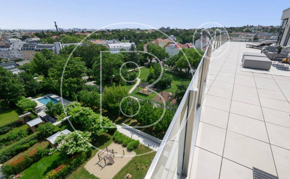 Blick von der Terrasse auf einen weitläufigen Gemeinschaftsgarten mit Pool und Spielplatz.