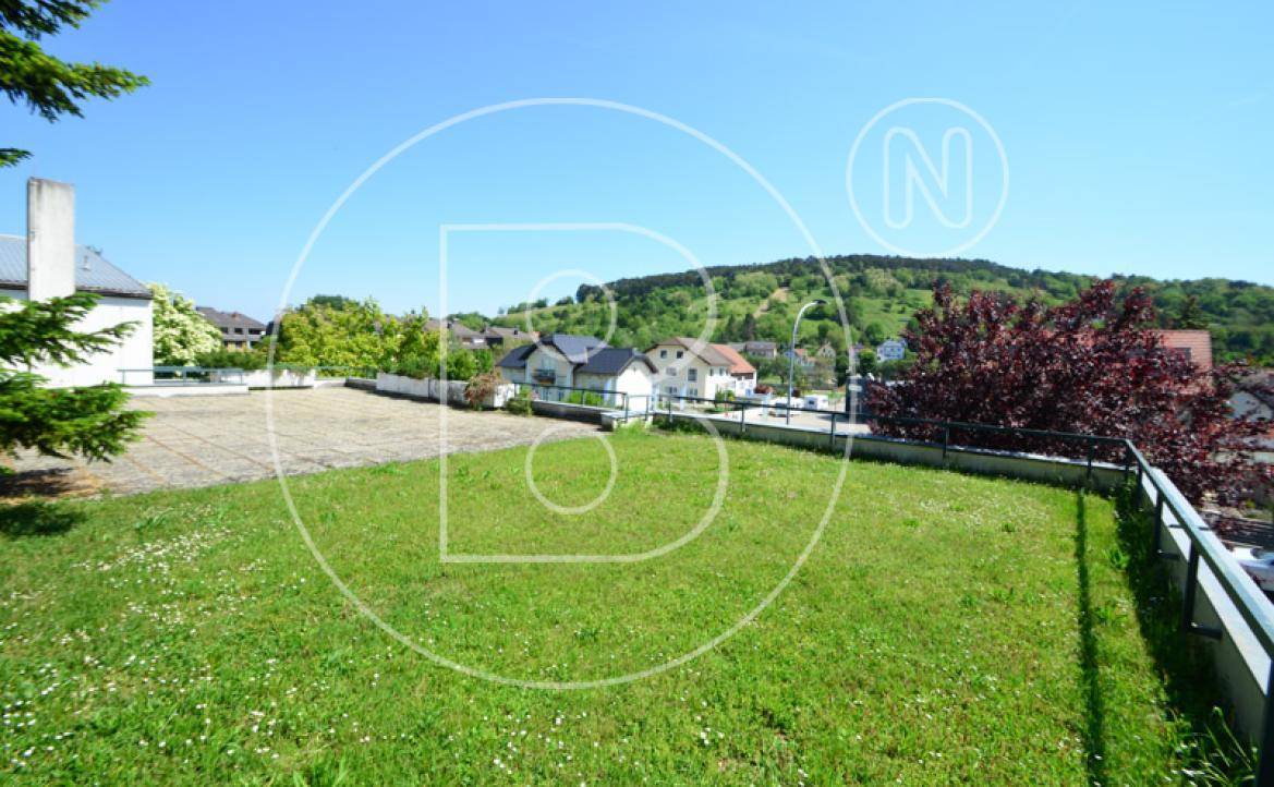 Große Rasenfläche mit Blick auf die umliegende Landschaft und Häuser in der Ferne.