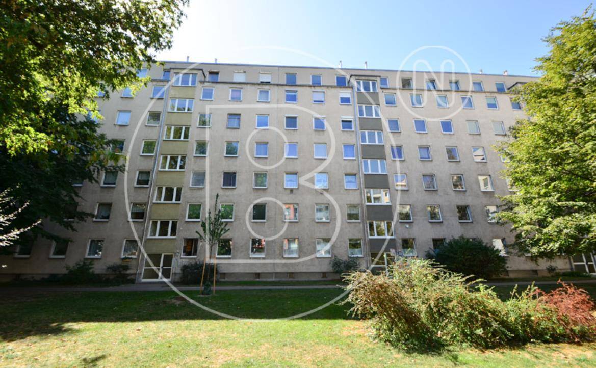 Mehrfamilienhaus mit vielen Fenstern und einer gepflegten Grünfläche im Vordergrund.