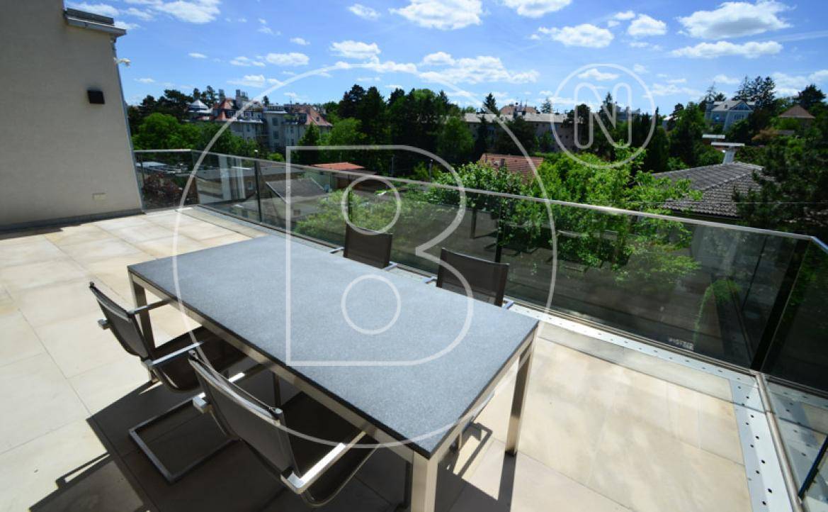 Sonniger Terrassenbereich mit modernem Esstisch und Panoramablick über die Umgebung.