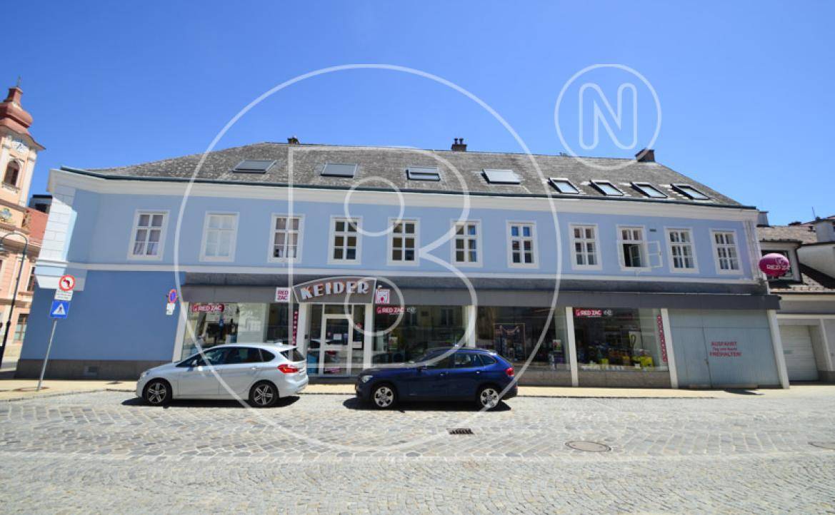 Fassade eines historischen Gebäudes mit Geschäften im Erdgeschoss und Wohnungen darüber.