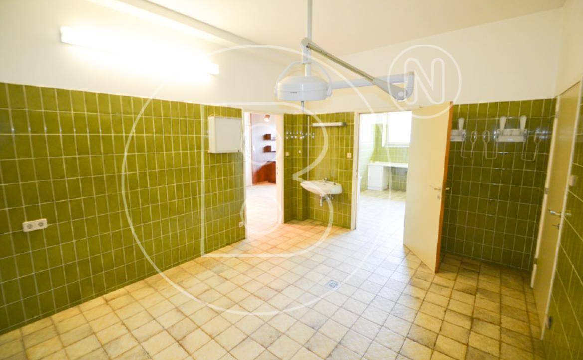 Großer Raum mit grünen Wandfliesen, Fliesenboden und Waschbecken, ideal als Hauswirtschaftsraum.