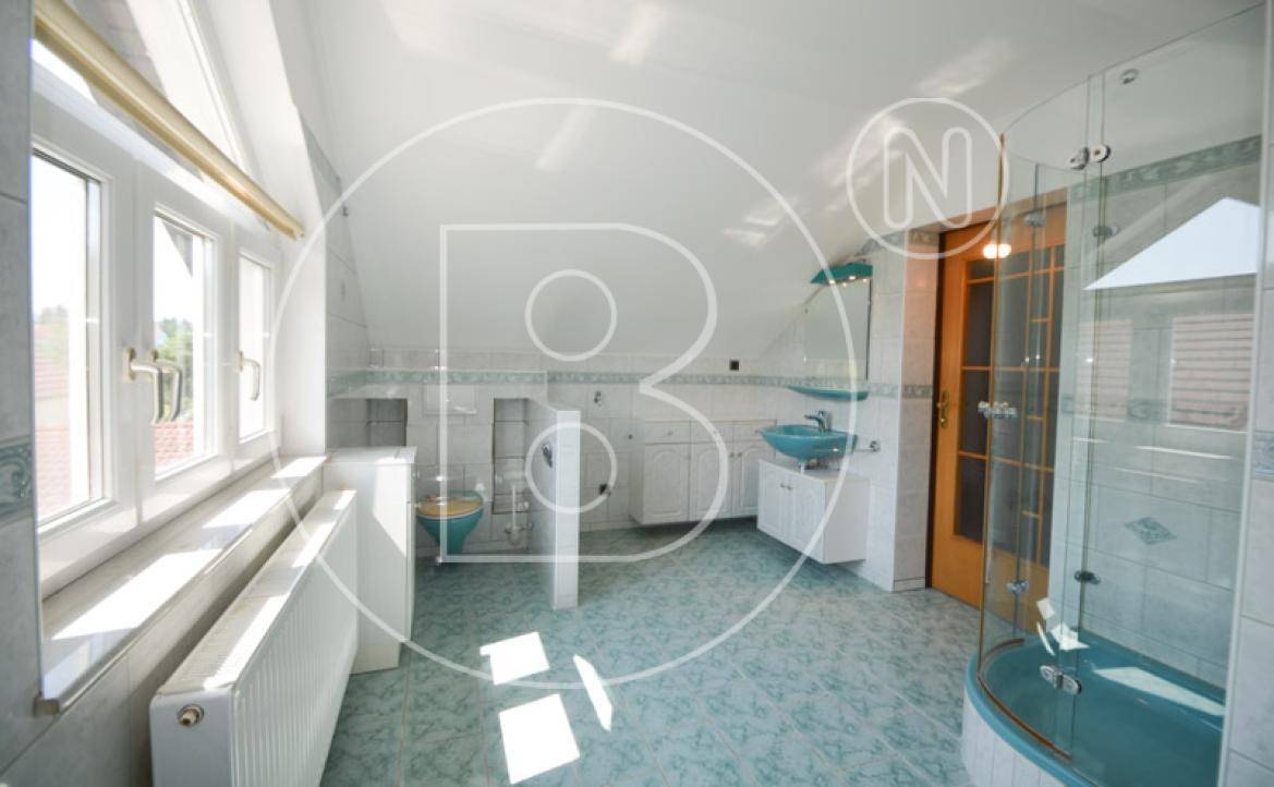 Helles Badezimmer im Dachgeschoss mit Eckbadewanne, Dusche und hellblauen Fliesen.