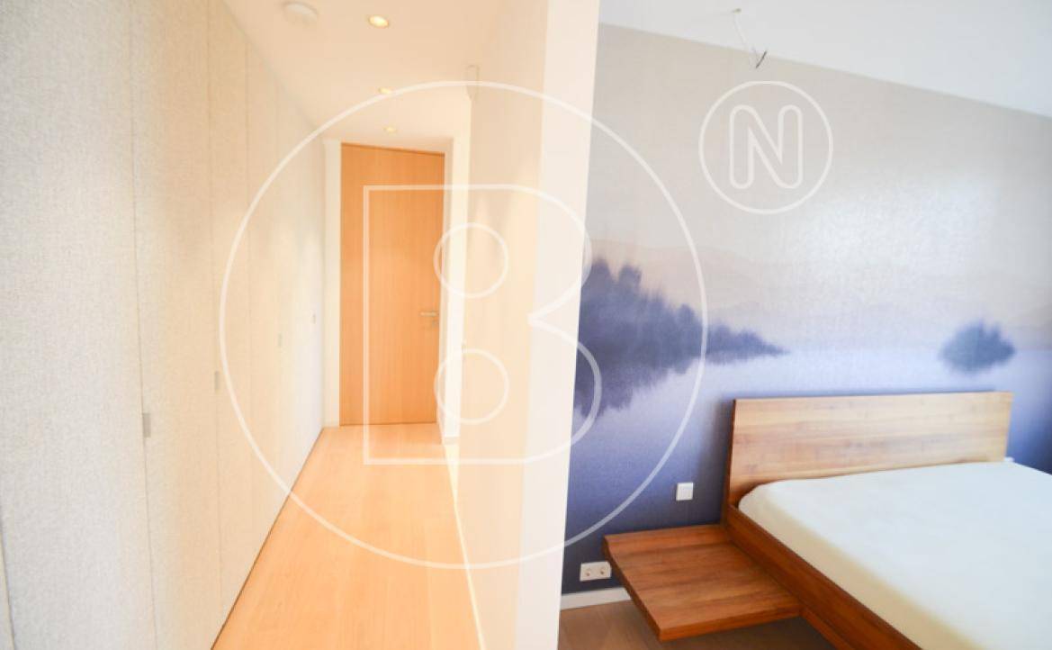 Schlafzimmer mit Holzboden, integrierten Kleiderschränken und moderner Wanddekoration.