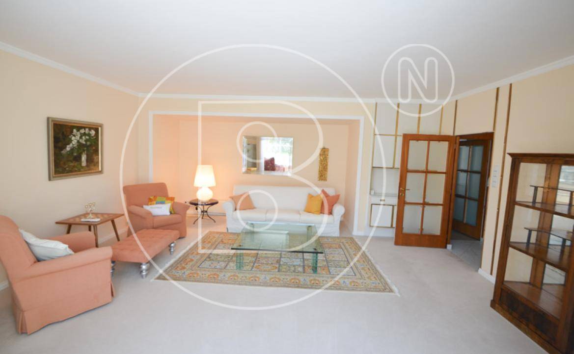 Helles Wohnzimmer mit Teppichboden, beigen Wänden und klassischer Einrichtung.