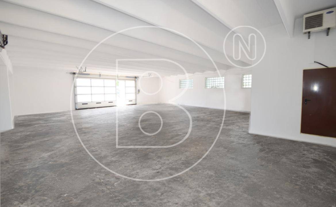 Geräumige, leere Garage oder Lagerhalle mit Betonboden und großem Rolltor.